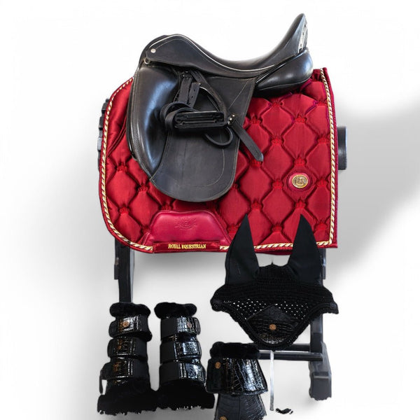 Black dressage saddle on red satin saddle pad with matching black boots