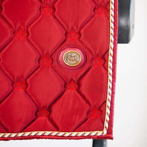 Detailed view of gold emblem on quilted red saddle pad