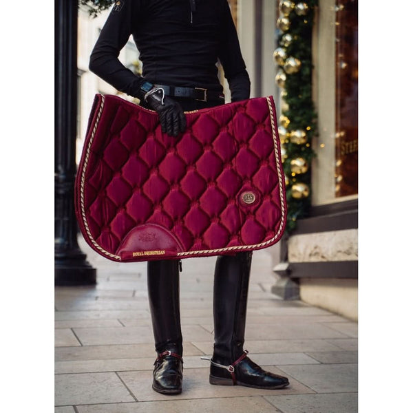 Royal Equestrian Rider holding a red quilted saddle pad in an outdoor setting